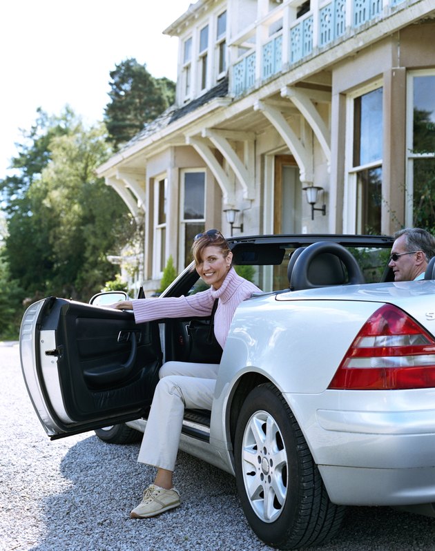 Woman stepping out of car in driveway, smiling, portrait