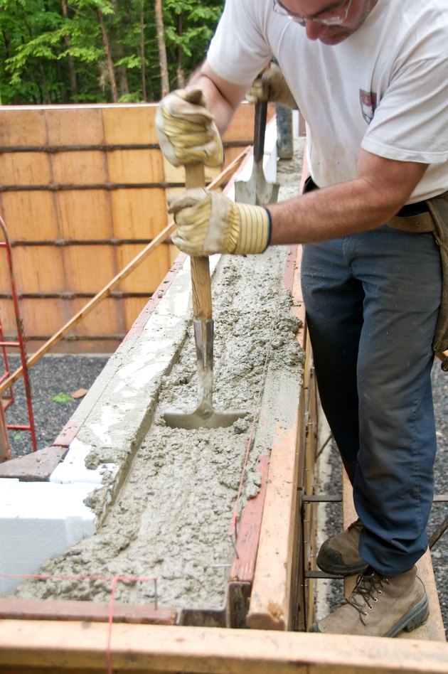 Construction worker stirring concrete inside mold