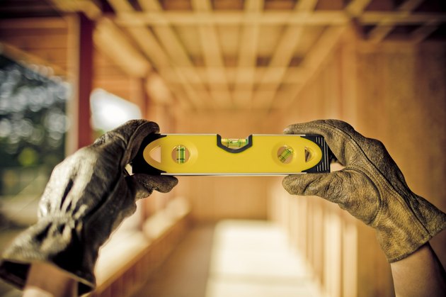 Hands holding a level, contruction in background