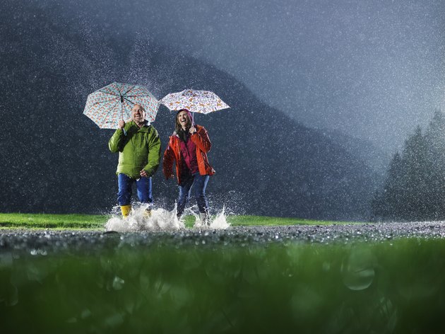 Man and woman with umbrellas playing in the rain.