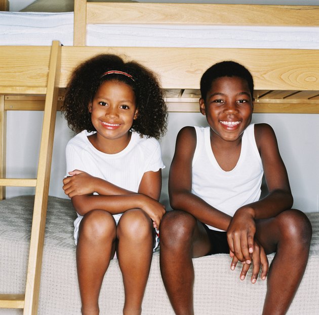 portrait of a young brother and sister sitting on a bed