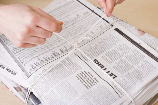 Hands tying stack of newspapers