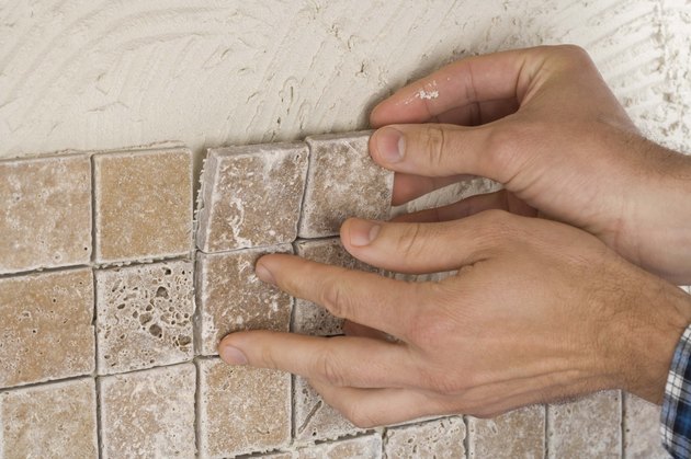 Person putting up tile on grout