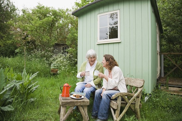 Mother and daughter sitting by garden shed