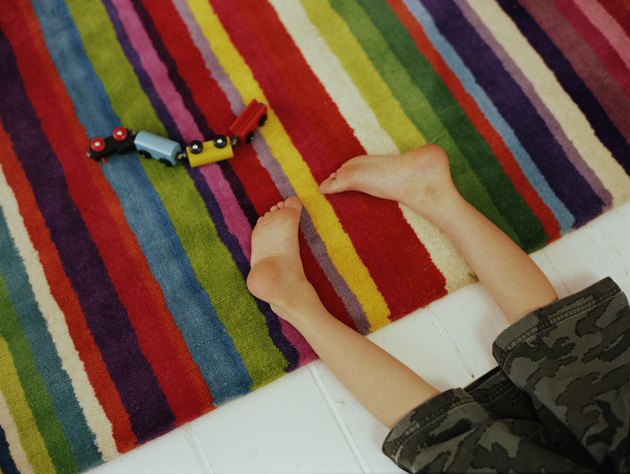 Boy (6-8) lying on floor by toy train, low section