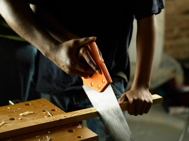 Hands sawing wood