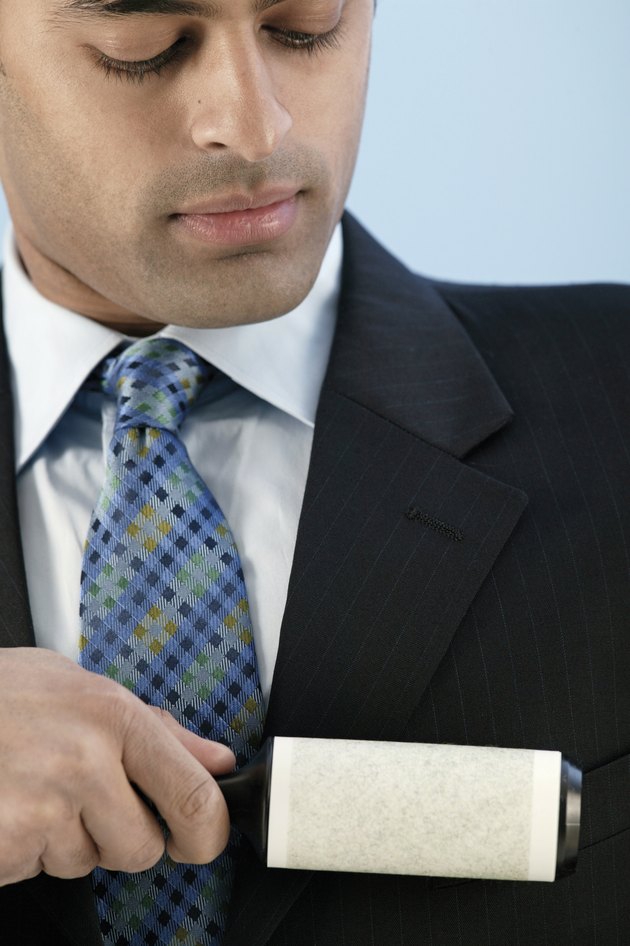Businessman using lint roller