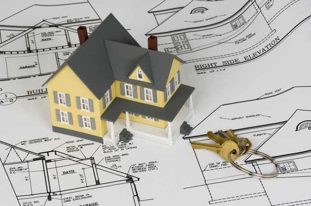 Miniature house with keys and blueprints
