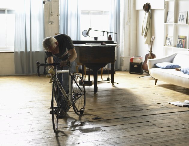 Mature man checking bicycle indoors