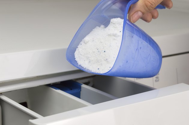 hand pouring detergent into the washing machine