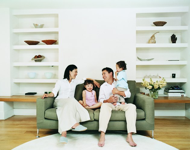 Smiling Family of Four Sitting on a Sofa in a Living Room