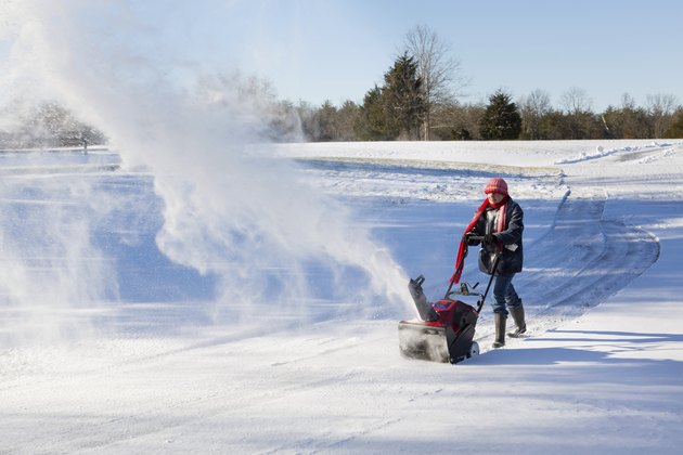 Senior woman clearing drive with snowblower