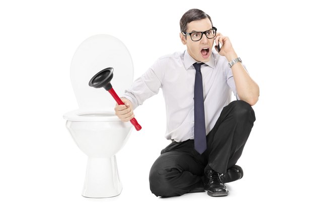 Angry man sitting by a toilet and talking on phone