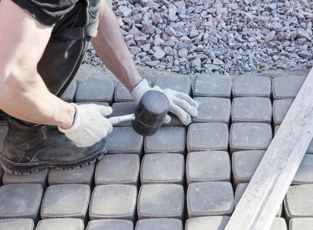 mason worker making sidewalk pavement with stone blocks
