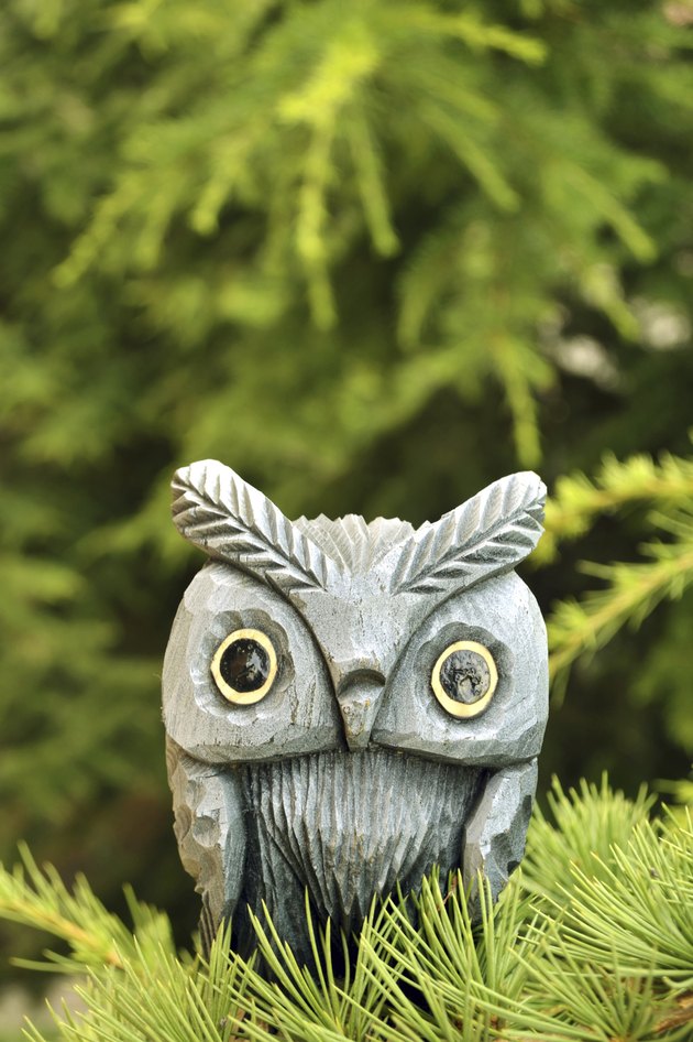 wooden owl statue on pine tree branch