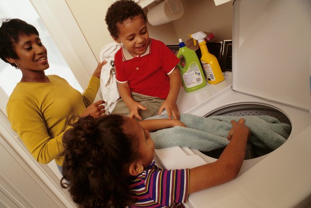 Mother with son and daughter (4-5) putting laundry into washing machine