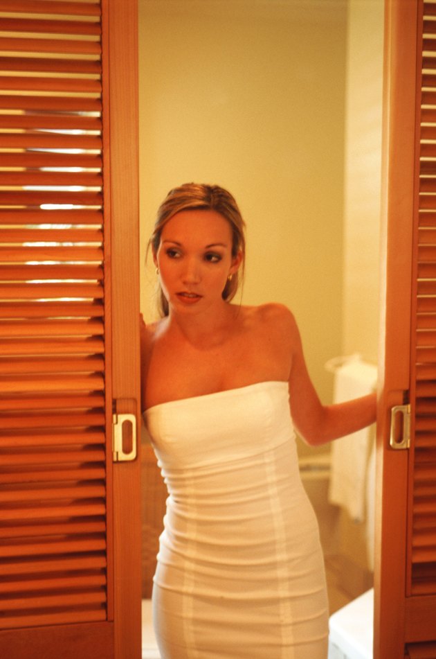 Young woman standing by open door, looking to side