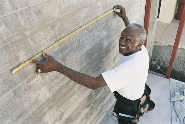 Elevated View of a Man Measuring a Wall With a Tape Measure