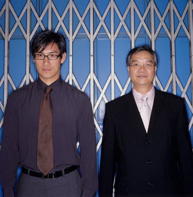 Two businessmen standing in front of sliding metal gate