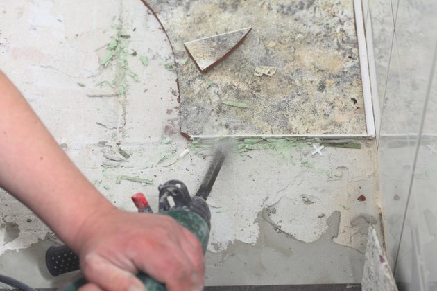 manual worker disassembling old floor tiles