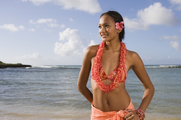 Woman in lei and bikini by ocean