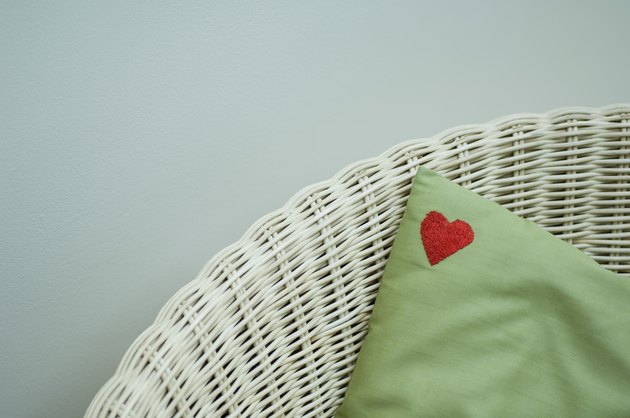 Red heart on corner of pillow in wicker chair