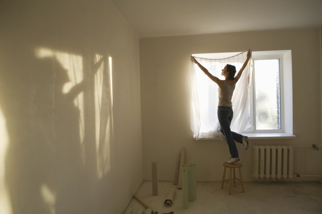 Woman fitting curtains in new apartment
