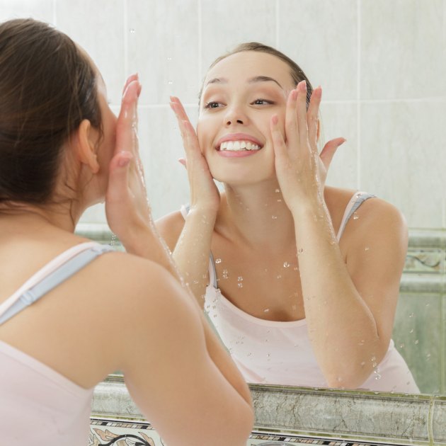 Young woman washing her face with clean water