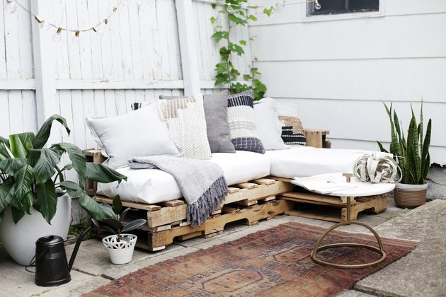 Drewniana kanapa na patio z białymi poduszkami i poduszkami.