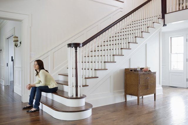 Mid adult woman sitting on stairs in entrance hall