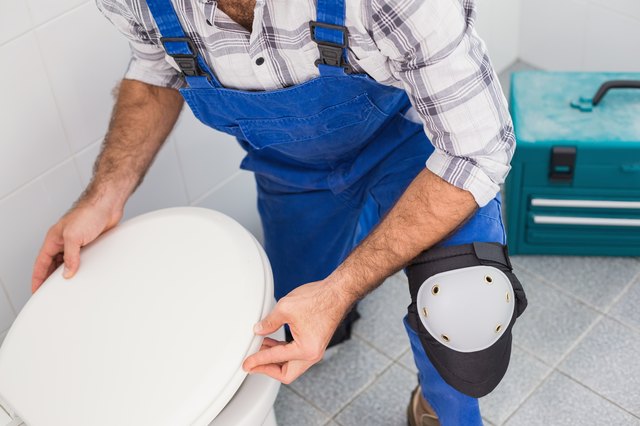 Plumber installing lid on toilet