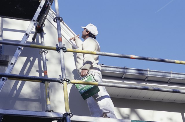 Man on scaffolding painting house, low angle