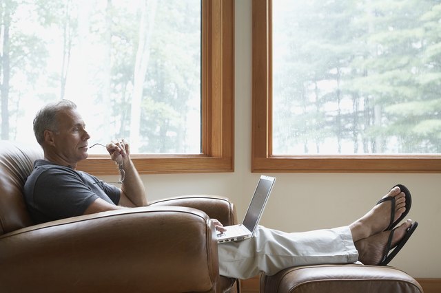 Man sitting in leather armchair using laptop