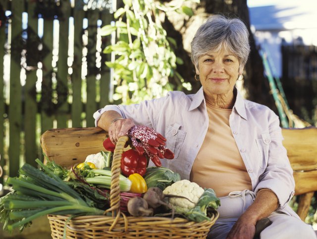 Senior woman with basket of vegetables, smiling, portrait