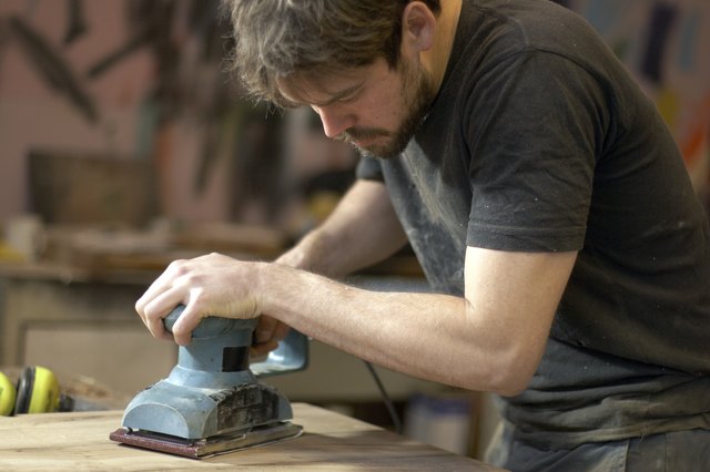 Carpenter Using An Electric Planer In Workshop