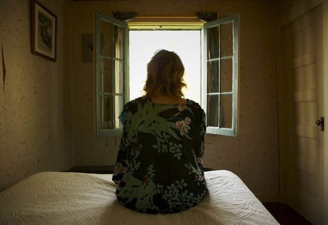 Woman sitting on bed looking out window