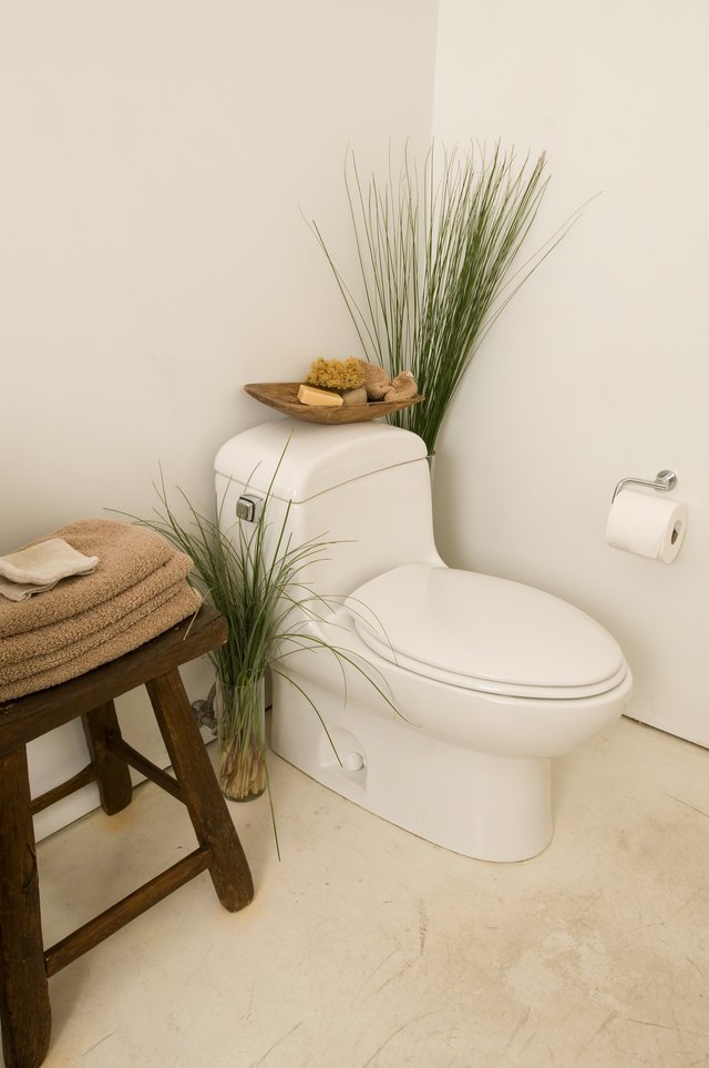 Corner of bathroom with toilet and towels on stool