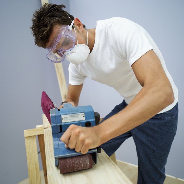 young man leveling a plank of wood with an electric sander