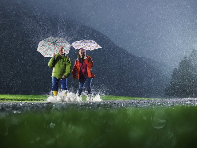 Man and woman with umbrellas playing in the rain.