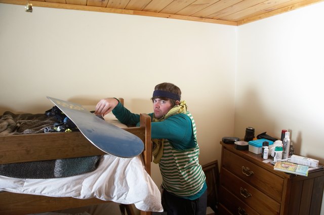Young man leaning on bunk bed with snowboard, portrait