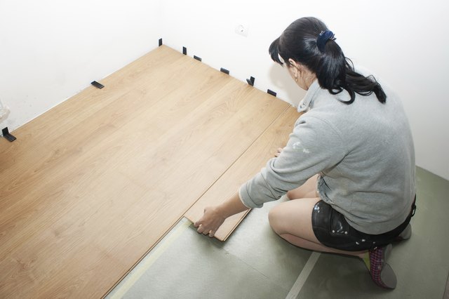 beautiful woman puts laminate flooring