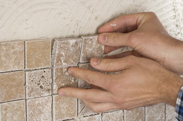 Person putting up tile on grout