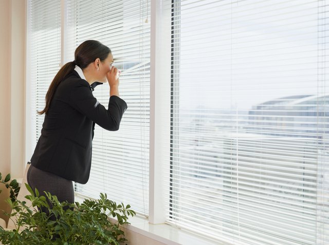 Mixed race businesswoman peering out window