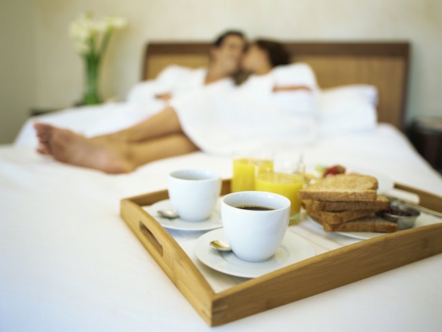 Breakfast on a bed with a young couple lying on bed in the background