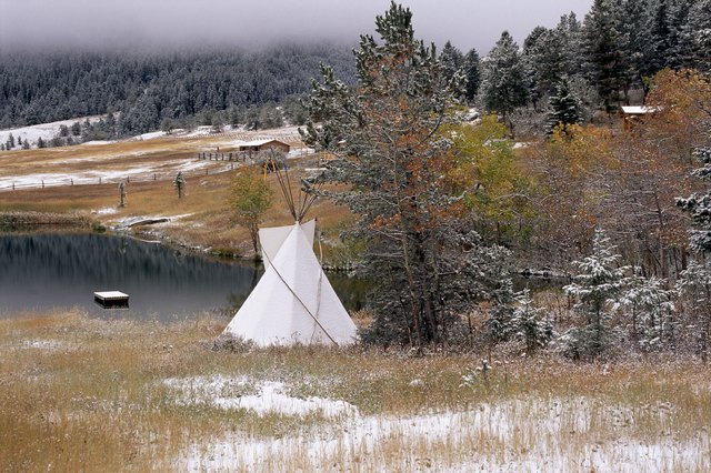 A view of an Indian teepee, patches of snow cover the ground