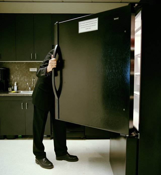 Mature businessman looking in refrigerator in office kitchen