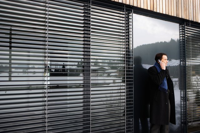 Man using mobile phone, snow-covered land reflected in windows