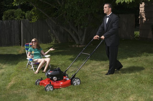 Mature woman sitting in deckchair, butler mowing grass