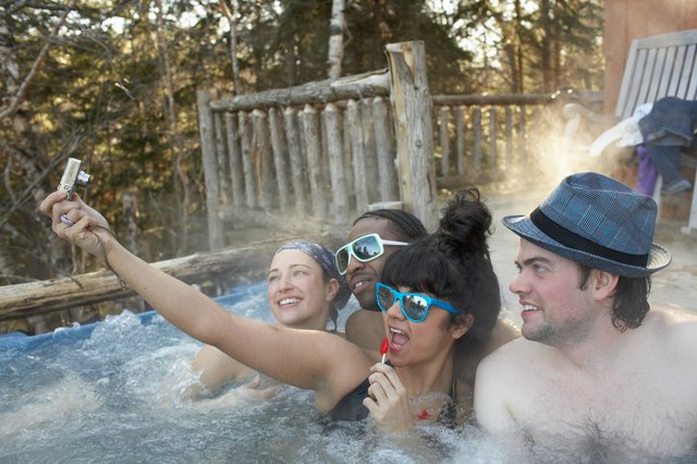 Young people frolicking in hot tub, taking digital self portrait