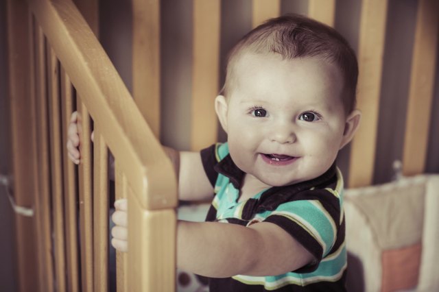 Happy baby standing up in his crib